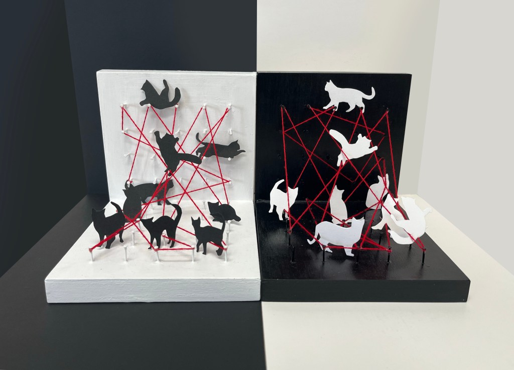 silhouettes of cats scattered amist red yarn stretched out onto nails on black and white wooden boards.